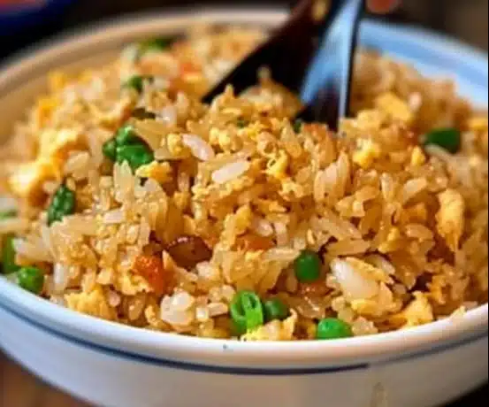 Bowl of easy egg fried rice topped with green onions and colorful vegetables