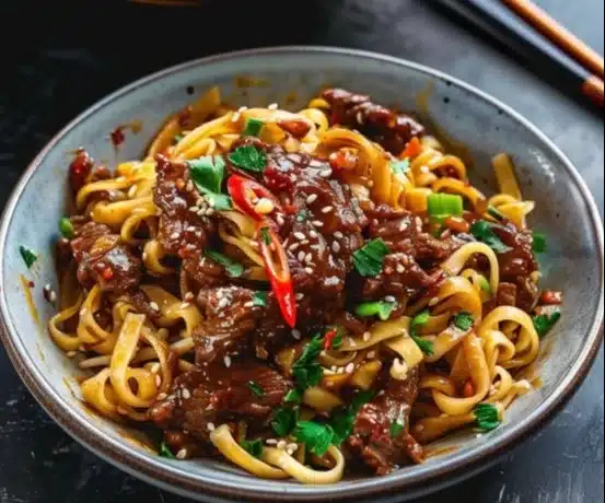 Delicious sticky beef noodles topped with fresh herbs and spices.