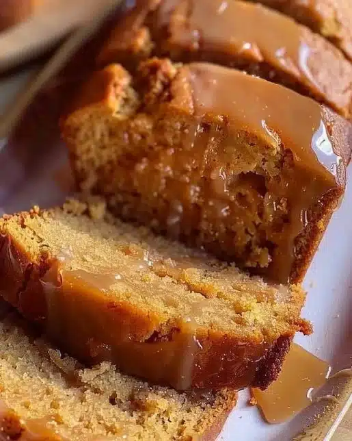 Brown butter pumpkin bread topped with salted maple glaze on a wooden table.