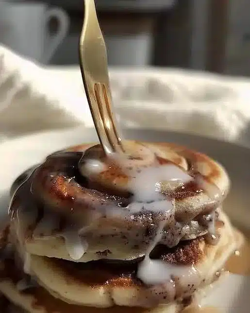 Delicious cinnamon roll pancakes topped with creamy icing and cinnamon swirls