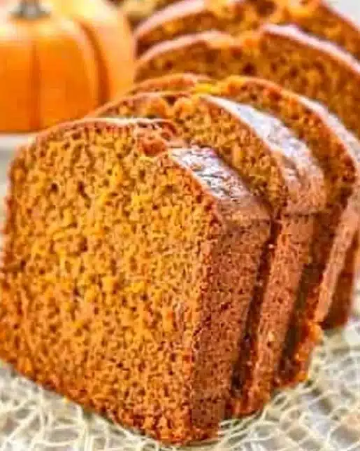 Moist pumpkin bread slice garnished with spices and served on a plate.