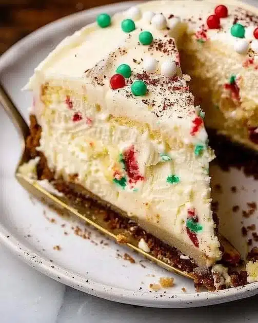 Delicious Sugar Cookie Cheesecake topped with colorful sprinkles on a dessert plate.