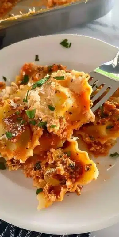 Million Dollar Ravioli Casserole topped with cheese and herbs in a baking dish