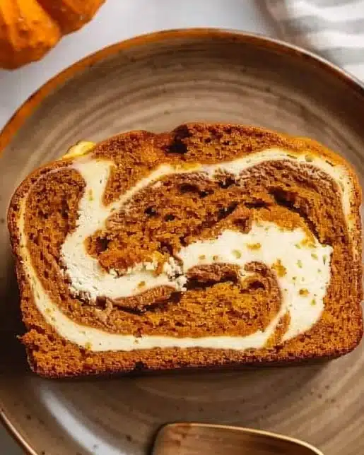 Delicious pumpkin bread with a creamy swirl of cream cheese on top.