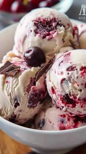 A bowl of creamy Cherry Garcia ice cream topped with cherries and chocolate chunks.