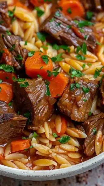 A bowl of Beef Giouvetsi with orzo pasta and tender beef stew.