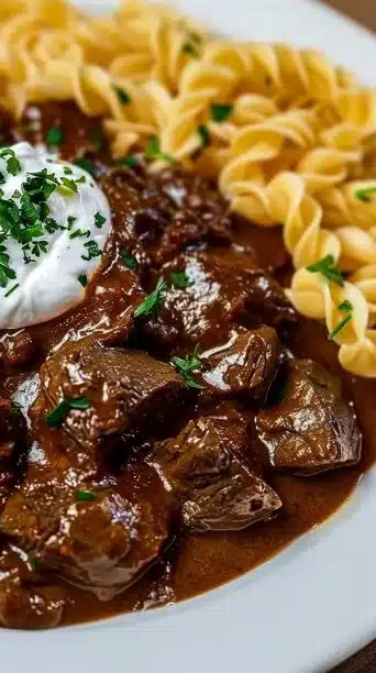 A bowl of creamy goulash garnished with herbs, showcasing German comfort food.